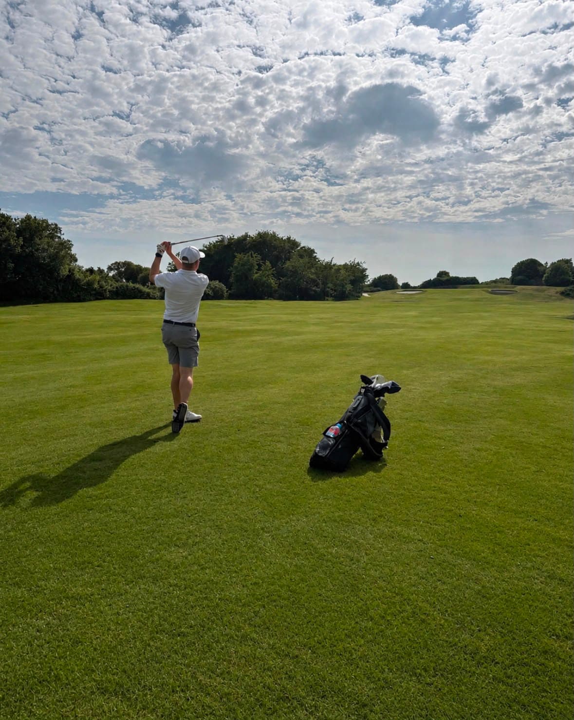A golfer holding the finish on an iron shot down the fairway